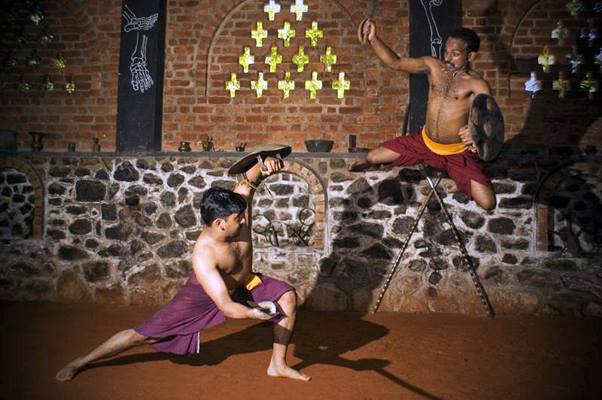 Dynamic Kalaripayattu aerial kick training with practitioner performing high jump attack while partner demonstrates defensive stance