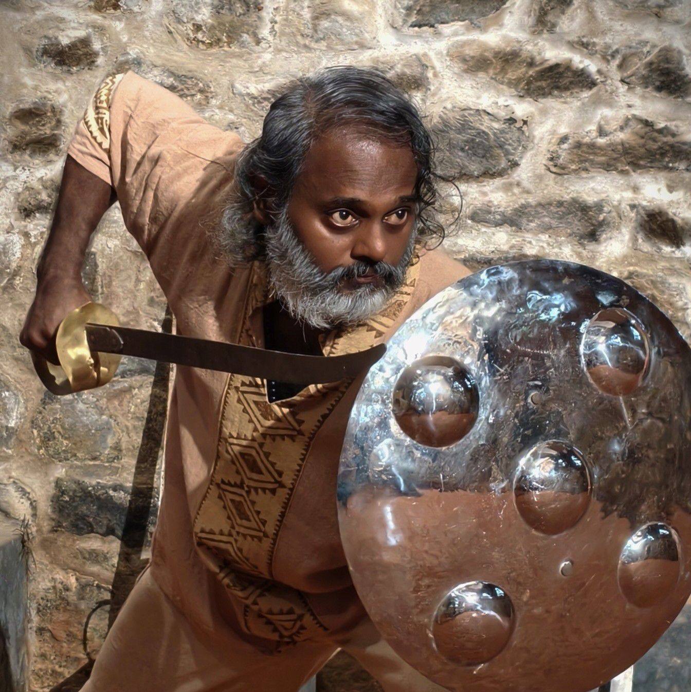 Kalaripayattu master demonstrating traditional combat stance with authentic Kerala shield and sword in stone training ground