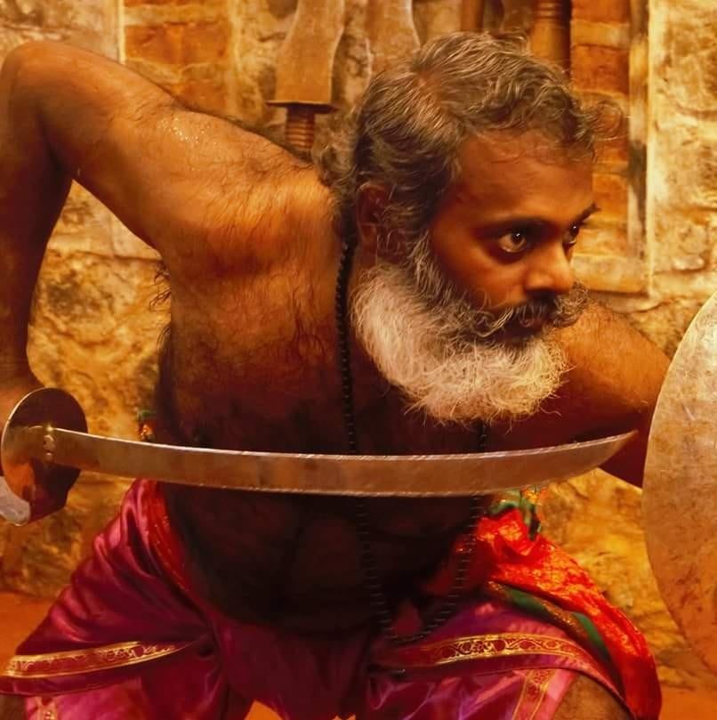 Kalaripayattu master in intense training pose with traditional sword demonstrating Kerala martial arts technique and skill