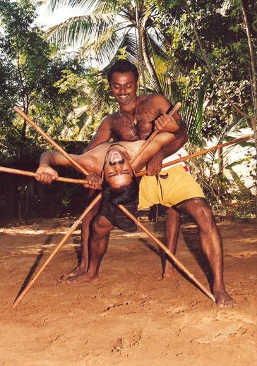 Outdoor Kalaripayattu spear and staff training in natural Kerala setting with practitioners demonstrating long weapon techniques