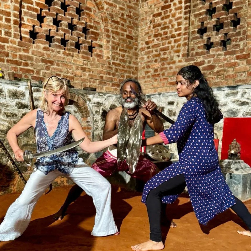 Kalaripayattu sword combat training session between practitioners in traditional Kerala martial arts academy with master supervision